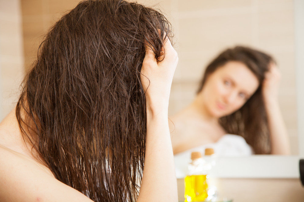 Woman applying oil to hair