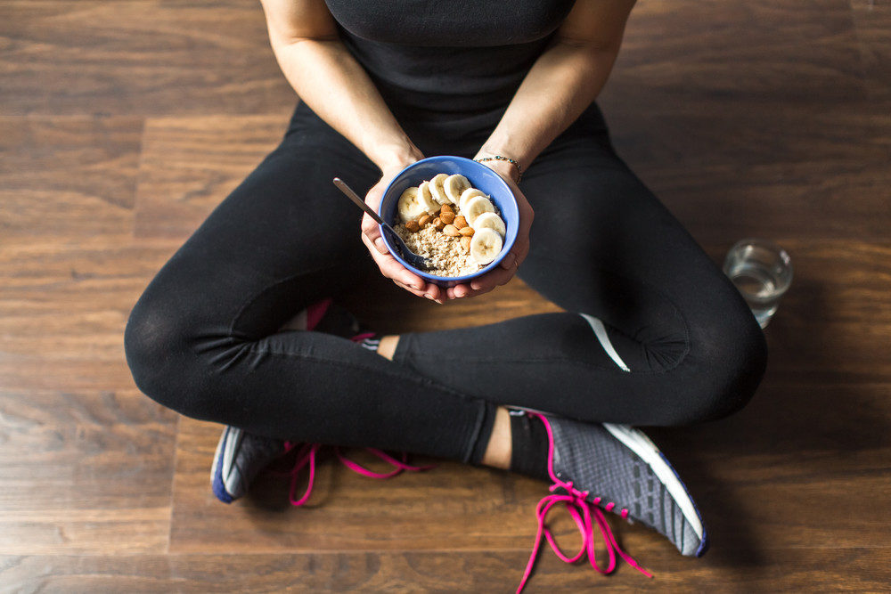 Woman in fitness clothes eating oatmeal